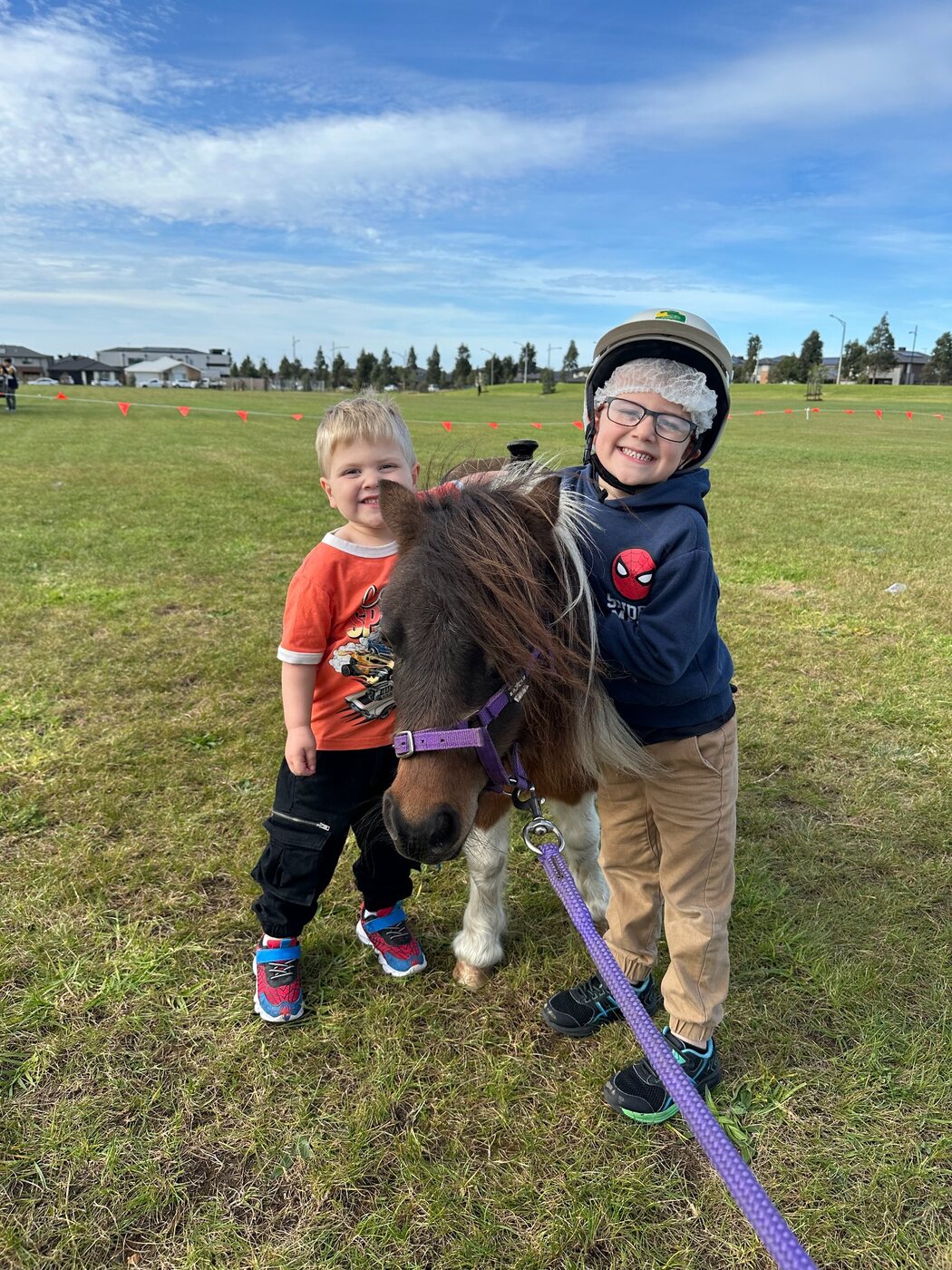 Two children meeting a Little Riders pony at an outdoor party