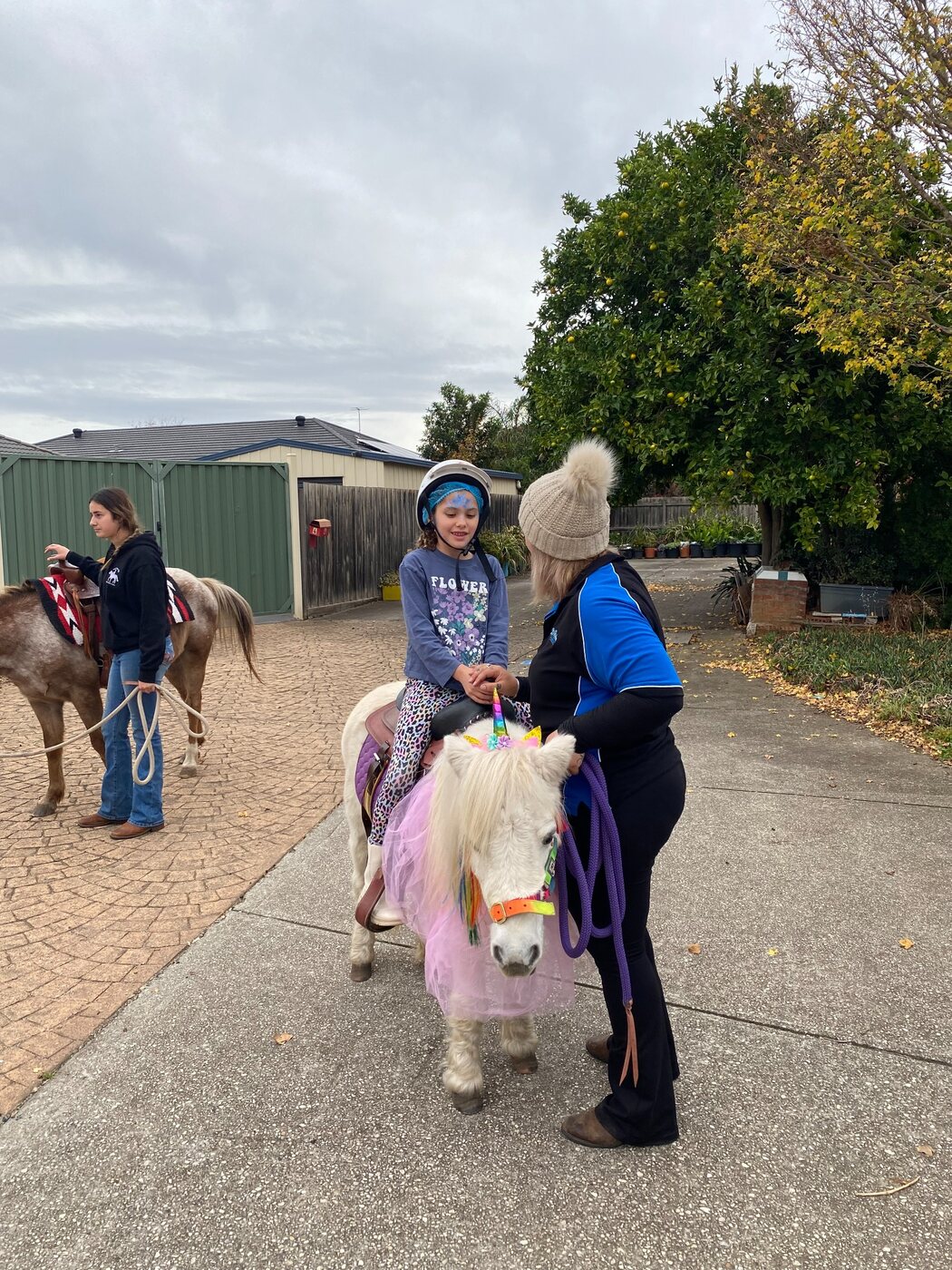 A child riding a decorated pony with a Little Riders handler