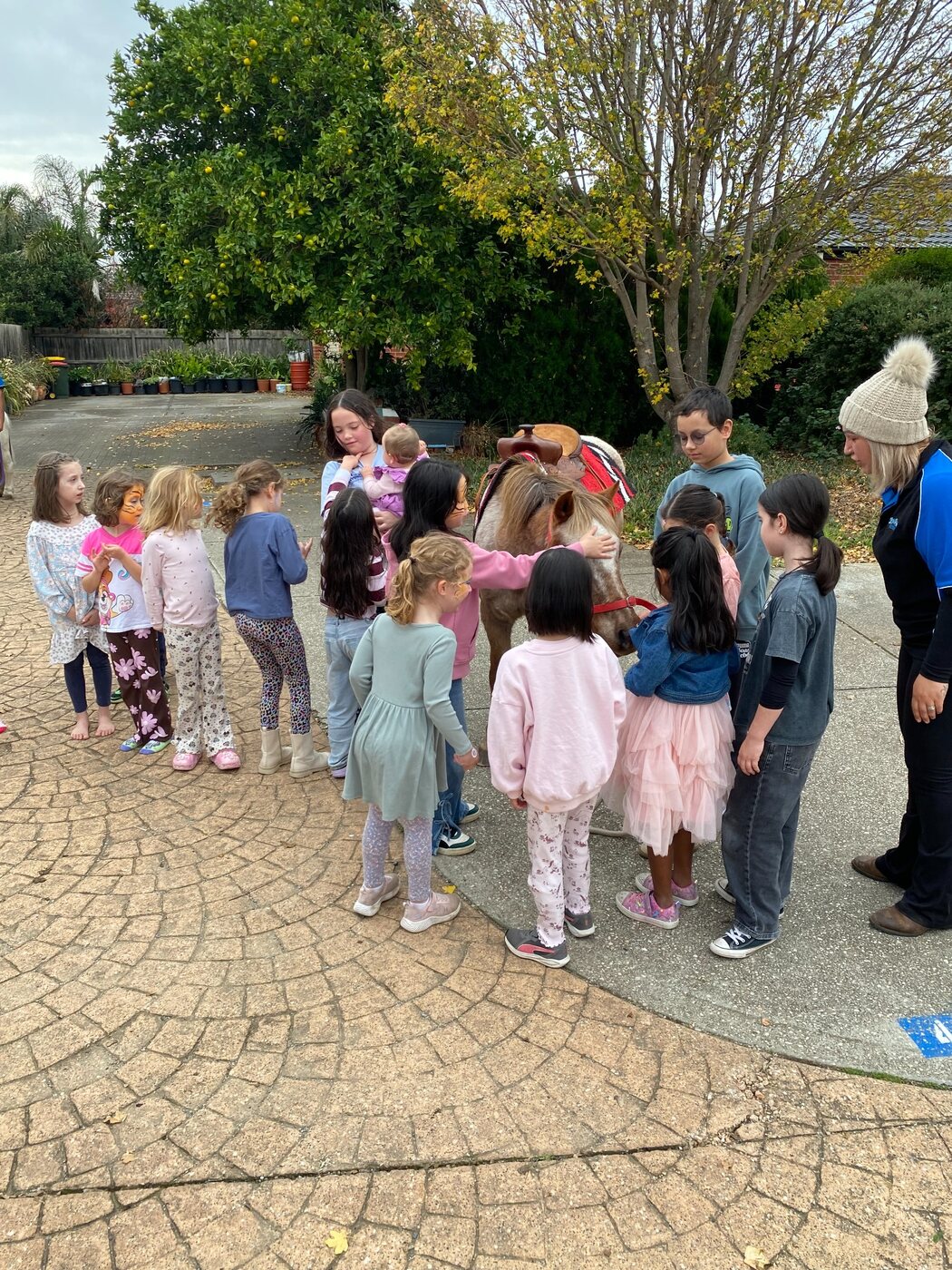 Children gathered safely around the ponies at a Little Riders party