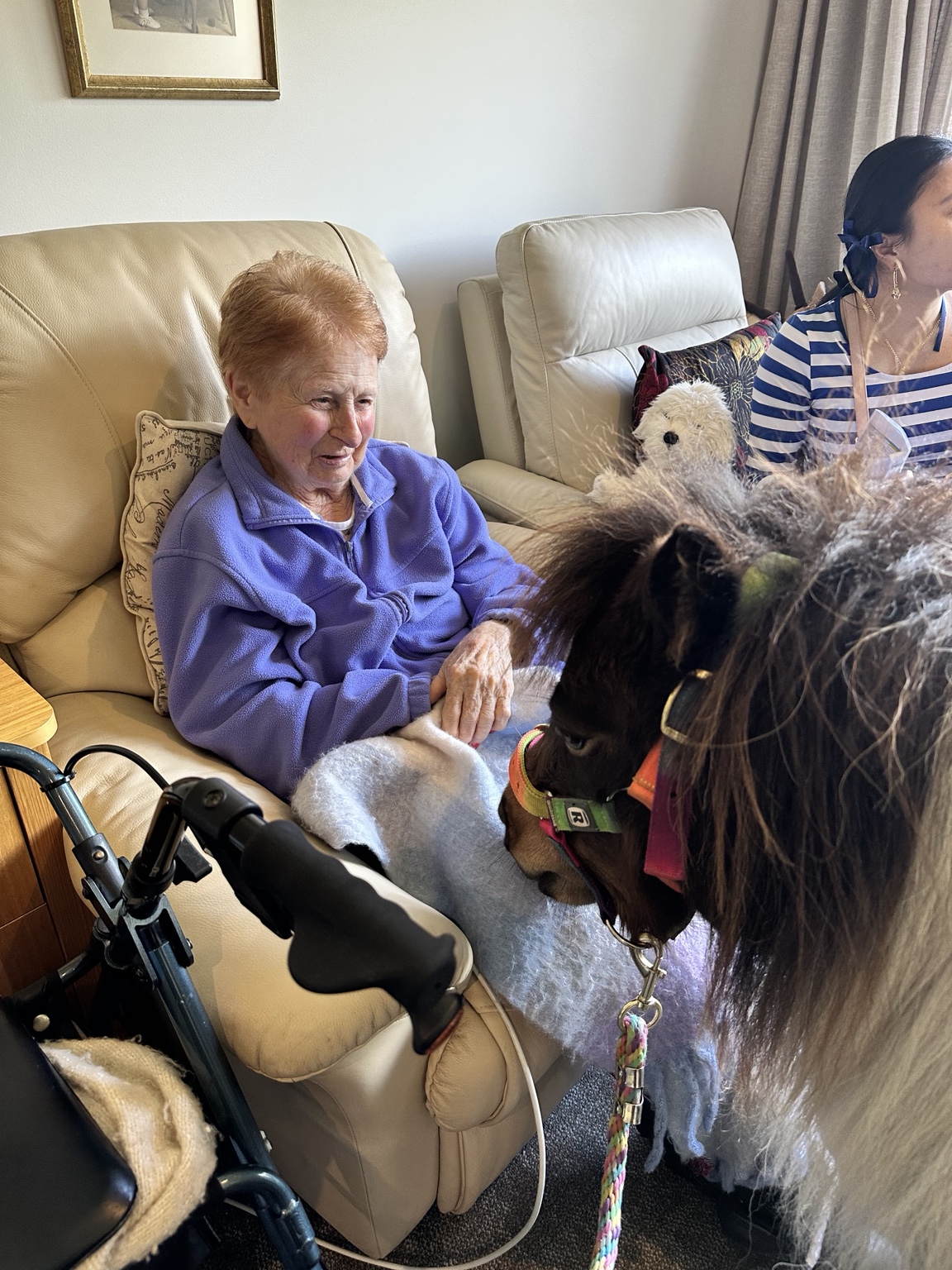 A resident meeting a miniature pony inside an aged-care home